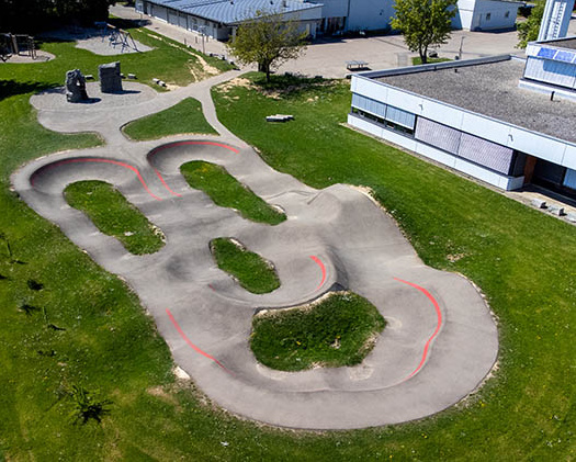 Gesamte Anlage des Pumptrack Staig als Luftbild, geschwungenes Layout neben dem Freizeitbereich