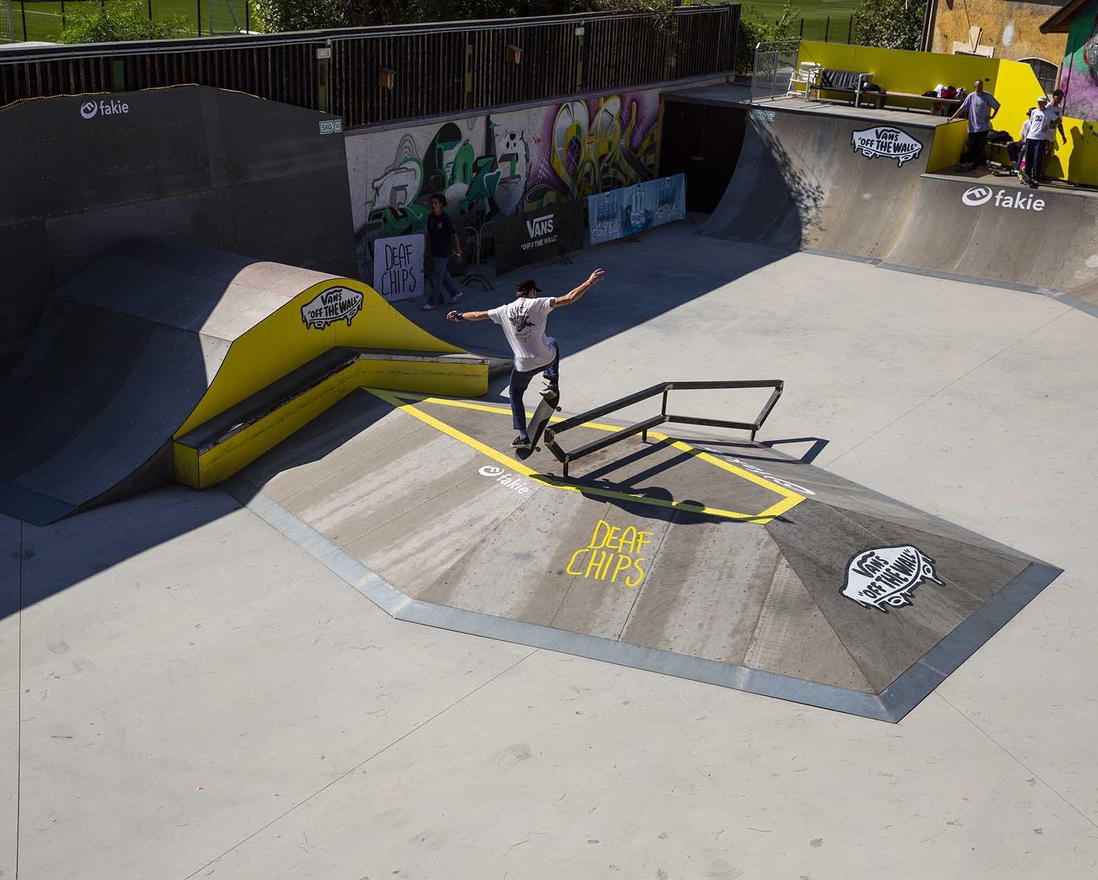 A skateboarder performing a trick on a rail over a ramp obstacle at the Meran skatepark.