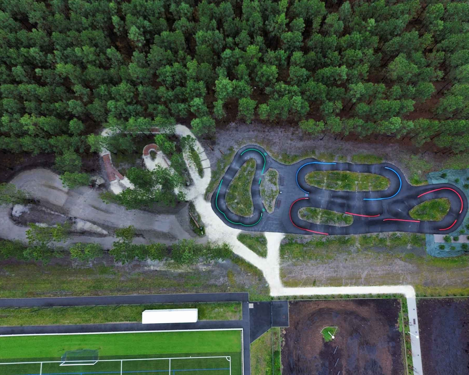Wide-angle view of Pumptrack Audenge, black asphalt tracks with green islands